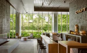a lobby with a bar with chairs and windows at Kimpton Maa-Lai Bangkok, an IHG Hotel in Bangkok