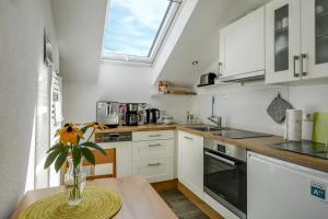 a kitchen with white cabinets and a vase of flowers on a table at Ferienwohnung Irmi in Hergensweiler +17 photos