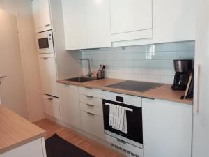 uma cozinha com armários brancos e um forno com placa de fogão em Kotimaailma Kuopio em Kuopio