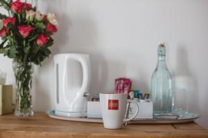 a table with two cups and a vase of flowers and a bottle at Ashburton Court Guest House in Ashburton