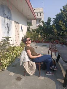 a woman sitting on a chair in front of a building at The Desire Hostel in New Delhi