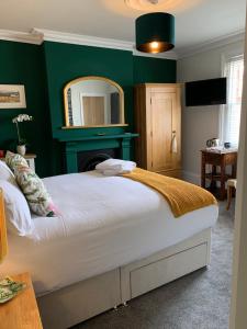 1 dormitorio con paredes verdes y 1 cama con espejo en THE LAZY LION, en Milford on Sea