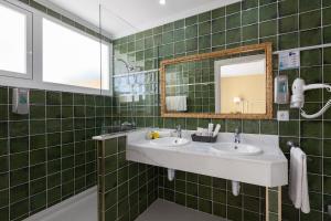 a green tiled bathroom with two sinks and a mirror at Hotel Araxa - Adults Only in Palma de Mallorca