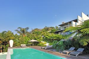 a swimming pool with two chairs and a building at Days At Sea Beach Lodge in Trafalgar