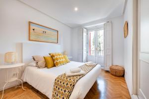 um quarto branco com uma cama com almofadas amarelas em MintyStay - Fernando VI em Madri