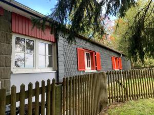 ein Haus mit roten Fenstern und einem Zaun in der Unterkunft Baude Steinheid am Rennsteig mit 12 Betten in Steinheid