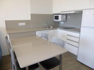 cocina con mesa y nevera blanca en Apart-rent Apartment Bahia 0022, en Empuriabrava