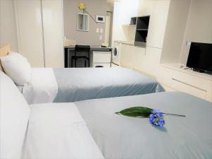 濟州的住宿－ARA Palace Hotel，酒店客房设有两张床,床上有一朵花
