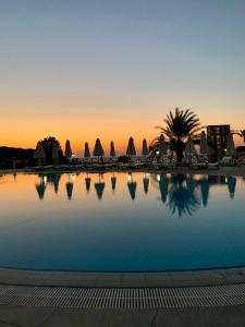 a swimming pool with a sunset in the background at Kaplica Hotel in Famagusta