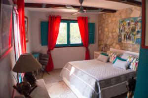 a bedroom with a bed and a window with red curtains at VILLA VOLUBILIS in Monserrat