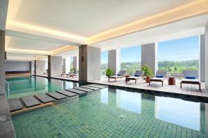 a swimming pool in a hotel with chairs and tables at Kokoon Hotel Banyuwangi in Banyuwangi