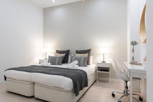 a white bedroom with a large bed and a desk at Cozy One-bedroom La Latina in Madrid