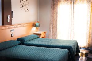 a hotel room with two beds and a window at Hotel El Cruce Chauchina in Chauchina