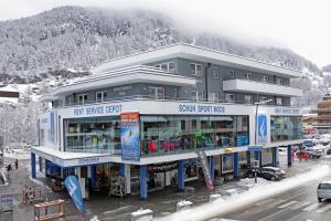 a large building with a snow covered mountain in the background at Appartement Sporthütte Fiegl in Sölden