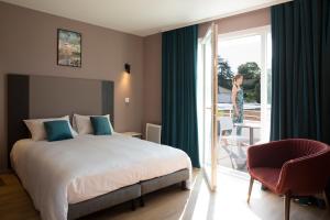 une chambre d'hôtel avec un lit et une femme donnant sur la fenêtre dans l'établissement Aïga Resort & Spa, à Châtel-Guyon