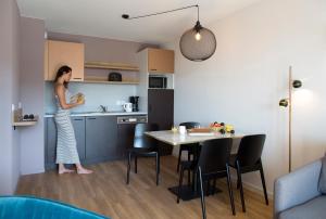 a woman standing in the kitchen of a apartment at Aïga Resort & Spa in Châtel-Guyon