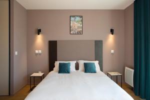 a bedroom with a large white bed with blue pillows at Aïga Resort & Spa in Châtel-Guyon