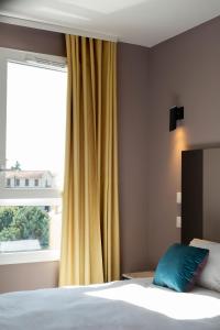 - une chambre avec un lit doté d'un rideau jaune et d'une fenêtre dans l'établissement Aïga Resort & Spa, à Châtel-Guyon