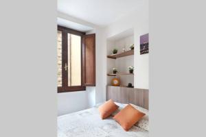 sypialnia z łóżkiem z pomarańczowymi poduszkami i oknem w obiekcie San Giuseppe Nido we Florencji