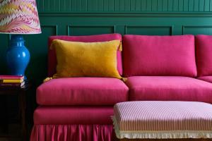 a pink couch with a yellow pillow next to a lamp at The Mitre, Hampton Court in Kingston upon Thames