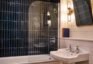 a bathroom with a sink and a shower and a tub at The Mitre, Hampton Court in Kingston upon Thames