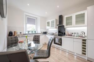 a white kitchen with a glass table and chairs at Casa Fresa - Union Heights in Dundee