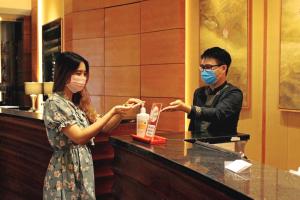 a man and a woman wearing face masks at a counter at Hotel Equatorial Ho Chi Minh City in Ho Chi Minh City