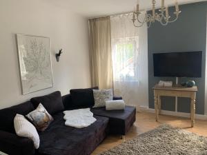 een woonkamer met een zwarte bank en een tv bij Sascha´s Home in Saarlouis