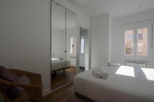 um quarto branco com uma cama e um espelho em 2 bedrooms 2 bathrooms furnished - Bernabeu - Business area with terrace - Minty Stay em Madri