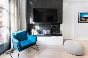 sala de estar con silla azul y TV en Luxury and cozy- 2 bedrooms 2 bathrooms -MintyStay- Herradores, en Madrid