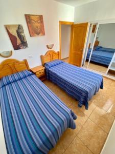 2 Betten in einem Schlafzimmer mit blau gestreifter Bettwäsche in der Unterkunft Apartamentos Sandra in Playa del Ingles