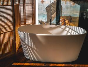 a white bath tub in a room with a window at Hotel La Zoologie & Spa Bordeaux in Bordeaux