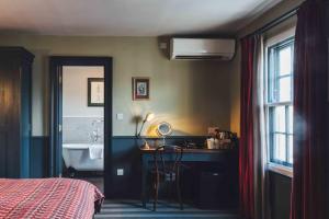 1 dormitorio con cama, escritorio y lavamanos en The Crown And Thistle, en Abingdon