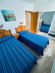 2 Betten in einem Zimmer mit blauer Bettwäsche in der Unterkunft Apartamentos Sandra in Playa del Ingles