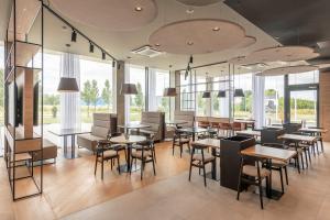 a restaurant with tables and chairs and windows at Park Inn by Radisson Vilnius Airport Hotel & Conference Centre in Vilnius