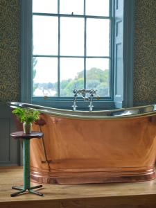 a large wooden tub in a bathroom with a window at The Mitre, Hampton Court in Kingston upon Thames