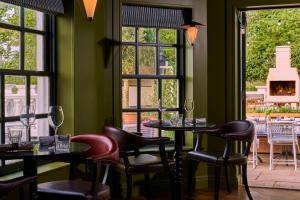 a restaurant with two tables and chairs and windows at The Mitre, Hampton Court in Kingston upon Thames