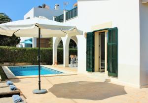 a white house with an umbrella and a swimming pool at Ca´n Sivinar mit Pool und Wifi in Cala Figuera