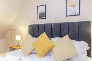 a bedroom with a bed with yellow and white pillows at Guest Homes - Hillbrook House Dwelling in Great Malvern