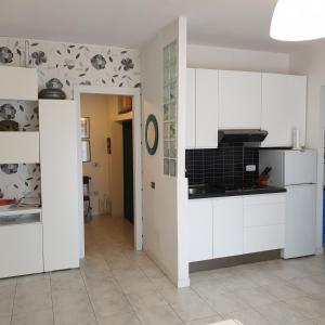 a kitchen with white cabinets and black and white wallpaper at Accogliente casa indipendente a 10 min dal mare in Castiglione della Pescaia