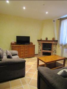 a living room with a couch and a table and a television at Casa Rural San Isidro in Valdepiélagos