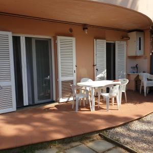 une terrasse avec une table blanche et des chaises. dans l'établissement Accogliente casa indipendente a 10 min dal mare, à Castiglione della Pescaia