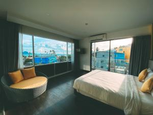 sypialnia z łóżkiem i krzesłem oraz dużym oknem w obiekcie Wake Up Aonang Hotel w Aonang Beach