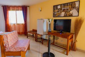 a living room with a tv and a table with a tv at Java Hotel in Toamasina