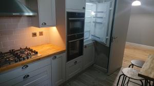 cocina con armarios blancos y fogones en Orchard Apartment, en Edimburgo