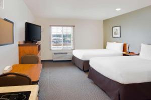 WoodSpring Suites Manassas Battlefield Park I-66 في ماناساس: غرفة فندقية بسريرين وتلفزيون بشاشة مسطحة