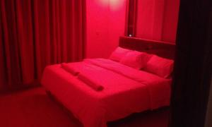 Dormitorio rojo con cama con sábanas y almohadas rojas en Hilda Blooms en Kisumu