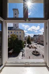 une fenêtre avec vue sur une ville dotée d'une tour d'horloge dans l'établissement Oysters & Bubbles Gastro Hotel. Rynok square, à Lviv