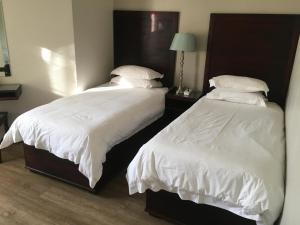 2 camas en un dormitorio con sábanas y almohadas blancas en Hydro Guesthouse, en Bloemfontein