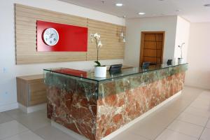 a lobby with a reception desk with a clock on the wall at Stop Way Hotel São Luís in São Luís